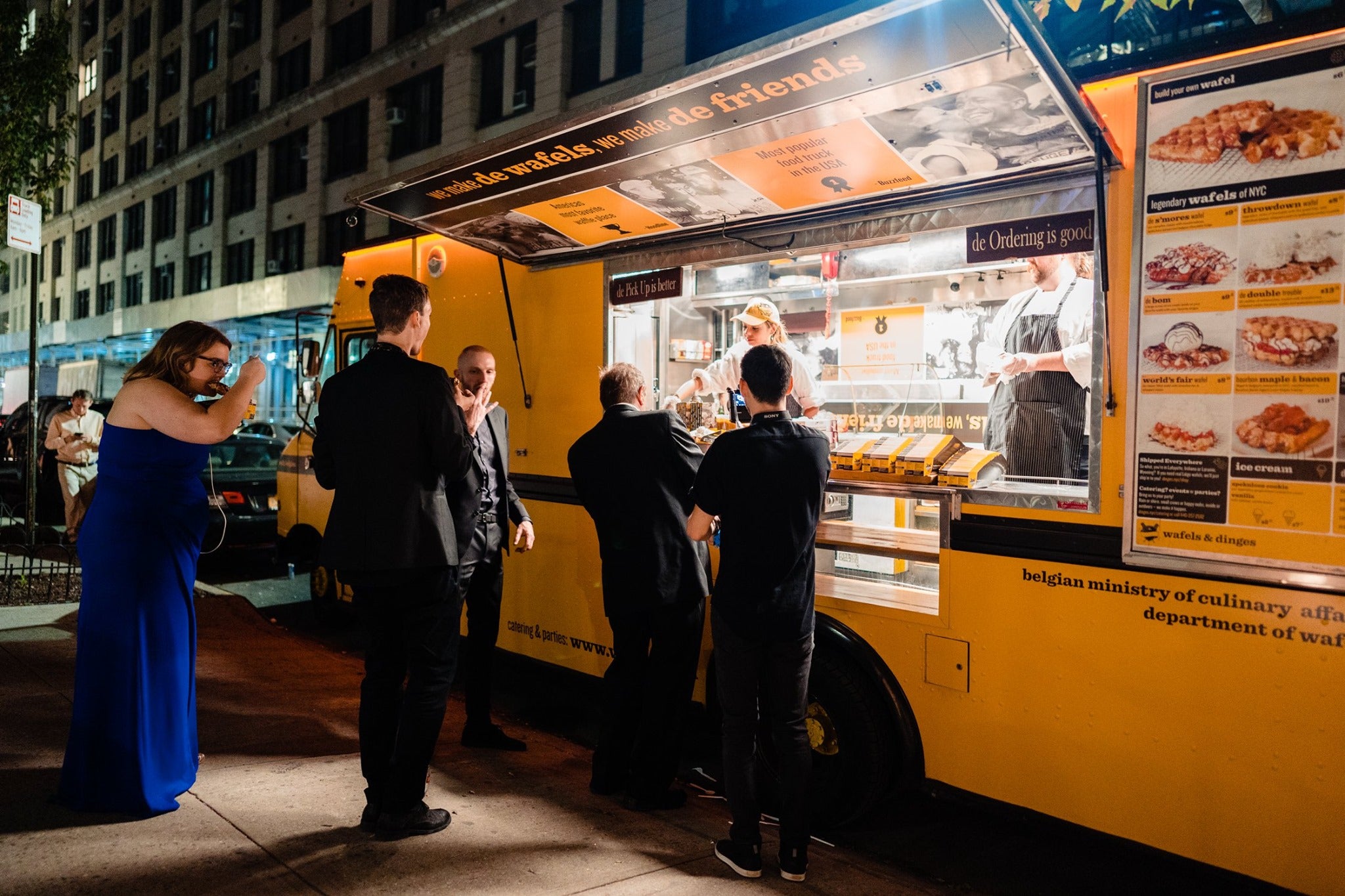 People enjoying waffles from wafel and dinges truck during a black tie event