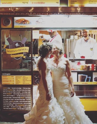 Two brides kissing in front  of a waffle cart
