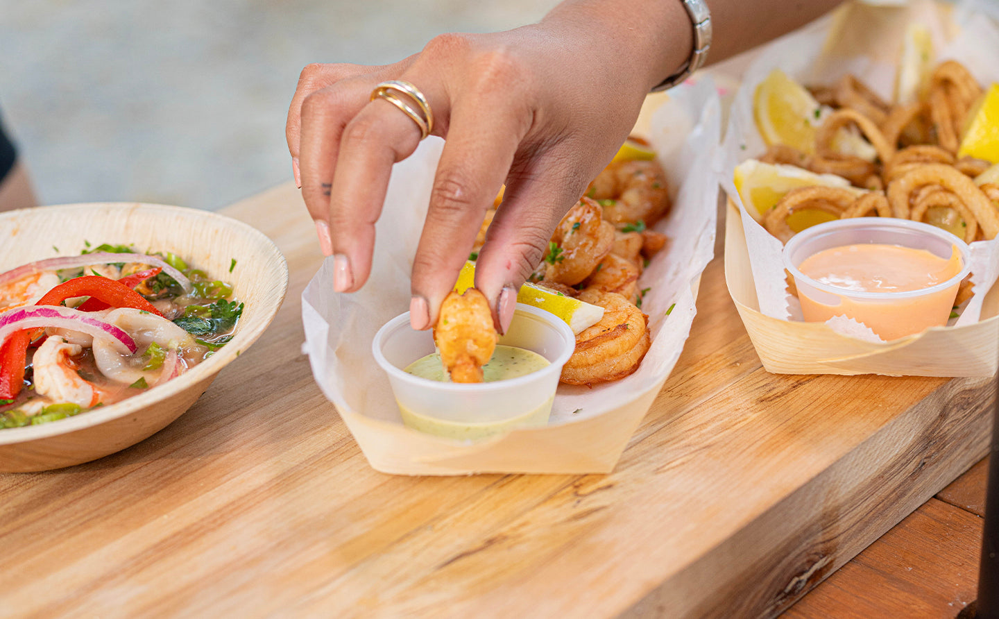 Someone dipping a prawn in  sauce